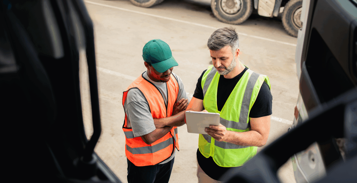 Two people talking while looking at a PrePass bypass mobile app on a tablet.