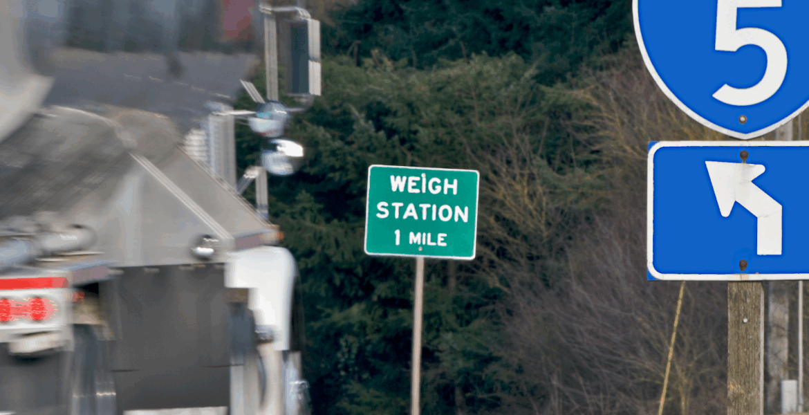 Sign showing a weigh station is 1 mile ahead. Weigh station bypass for fleets: Saving time, money, and operational costs.